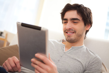 Portrait of a young relaxed men in a sofa using tablet