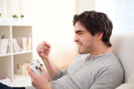 Young Attractive Man Playing Video Games Online In A Sofa