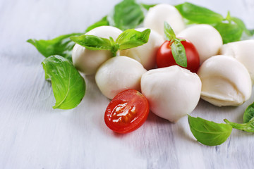 Tasty mozzarella cheese with basil and tomatoes, on wooden