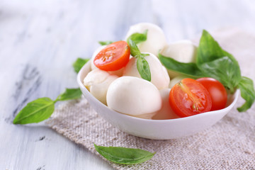 Tasty mozzarella cheese with basil and tomatoes in bowl,