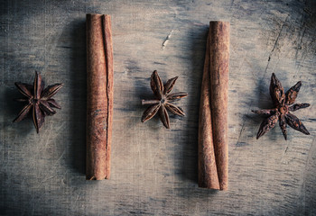Three anise stars and two cinnamon sticks on a wooden surface