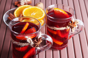 Mulled wine with oranges and spices on wooden background