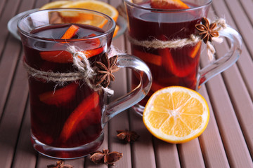 Mulled wine with oranges and spices on wooden background
