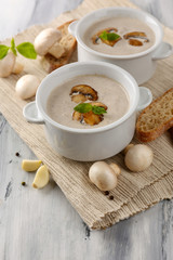 Mushroom soup in white pots, on napkin,  on wooden background