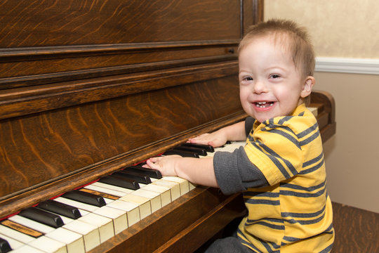 Laughing Down Syndrome boy playing on piano