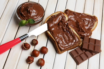 Bread with sweet chocolate hazelnut spread on wooden background