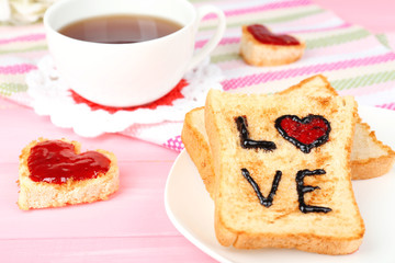 Delicious toast with jam and cup of tea on table close-up