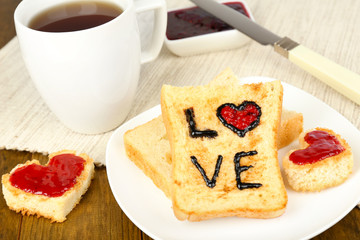 Delicious toast with jam and cup of tea on table close-up