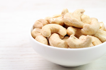 A white bowl with cashew nuts in it