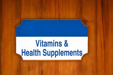 Vitamins, Health Supplements sign on wood background