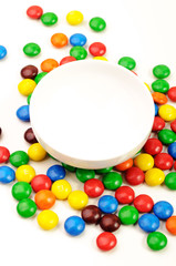 An empty white bowl and multicolor candies around