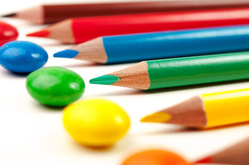 Naklejka premium Some colorign pencils pointing at the same color sweets