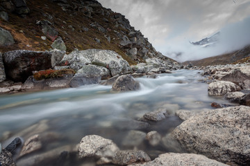 Green lake between mountains in cloudy day
