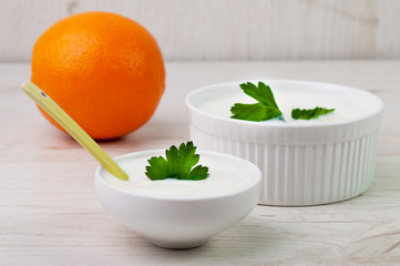 Two bowls with cream and an orange
