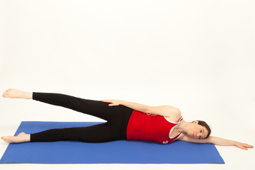 Die junge Frau macht Pilates &Uuml;bungen auf einer Matte