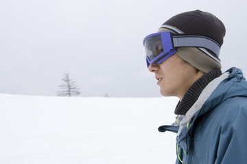 profile of man wearing goggles and standing still in snowy field