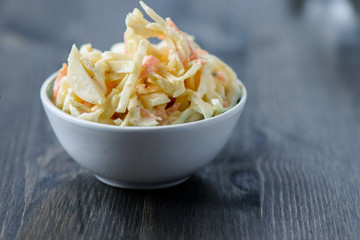 Coleslaw in a bowl on a wooden table - obrazy, fototapety, plakaty