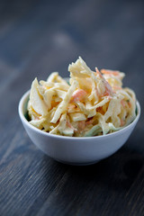 Coleslaw in a bowl on a wooden table - obrazy, fototapety, plakaty