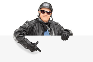 Mature biker pointing on a blank panel