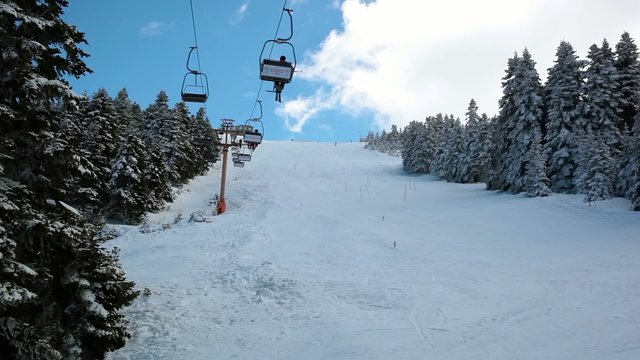 Ski Lift Moves Up Over The Ski Run surrounding By Snowy Forest.
