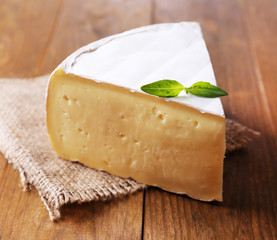 Tasty Camembert cheese with basil, on wooden table