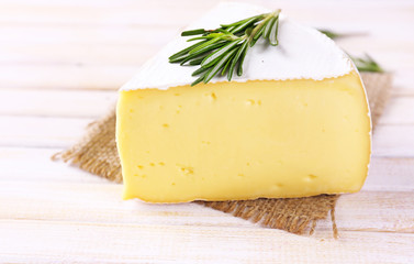 Tasty Camembert cheese with rosemary, on wooden table