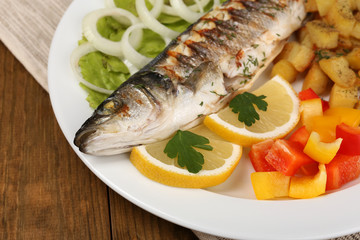 Delicious grilled fish on plate on table close-up