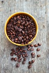 Coffee beans in bowl on wooden background