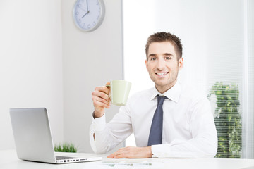 Businessman working on computer and drinking coffee.