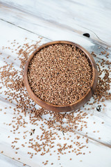 Above view of a wooden bowl with raw buckwheat