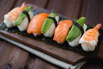 Wooden chopping board with a sushi set, studio shot, close-up