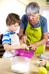 Senior woman helping grandson to cook and bake