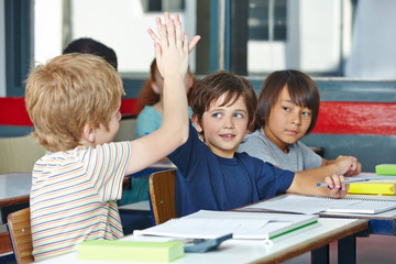Fototapeta na wymiar Schüler in Grundschule klatschen sich mit Händen ab