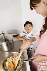 boy talking to mother cooking