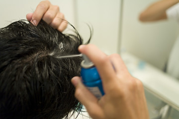 man applying hair restoration tonic to head