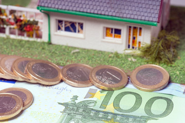 Eigenheim mit Euromünzen und Geldschein