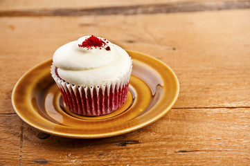 Cupcake on plate over wood background