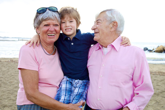 Happy cute kid hugging grandparents in vacation