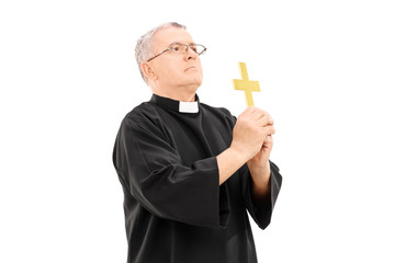 Mature reverend holding a holy cross and praying to god