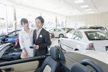 Fototapeta na wymiar husband and wife looking at cars in showroom