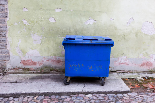 Blue Dumpster Against A Bright Green Wall