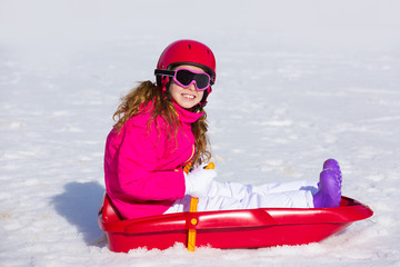 Kid girl playing sled in winter snow