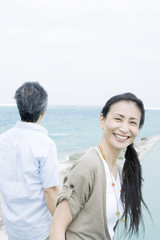 husband gazing at sea and smiling wife turning around 