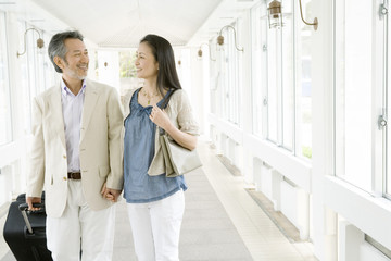 Obraz premium husband and wife holding hands and walking with suitcase