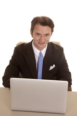 Man in suit at computer top view smile