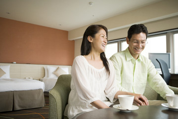 middle aged husband and wife laugh in hotel room