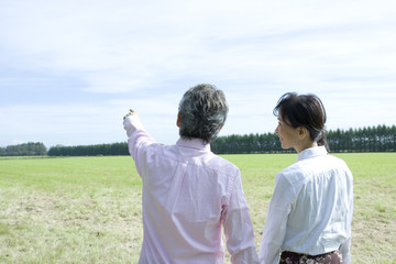 rear view of senior husband and wife standing on field