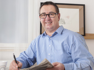 Man with glasses reading newspaper
