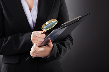 Businesswoman With  Magnifying Glass And Clipboard