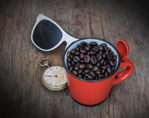 Coffee beans in cup on wood background